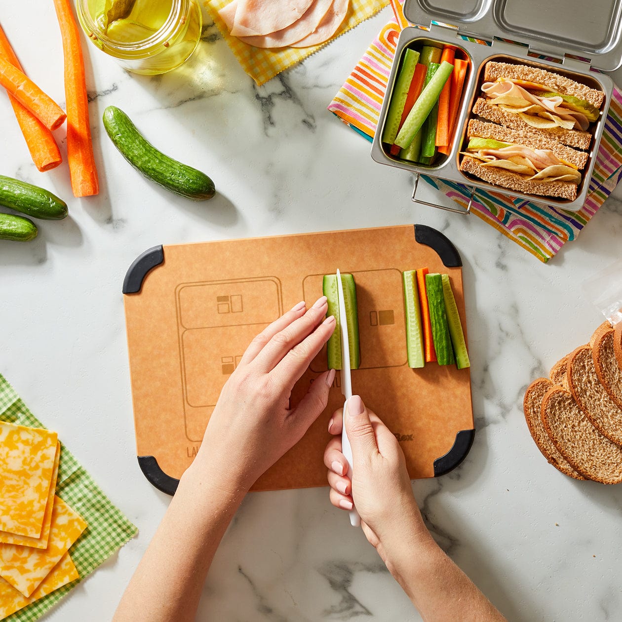 PlanetBox Prep to Pack cutting board with vegetables being prepared on top.