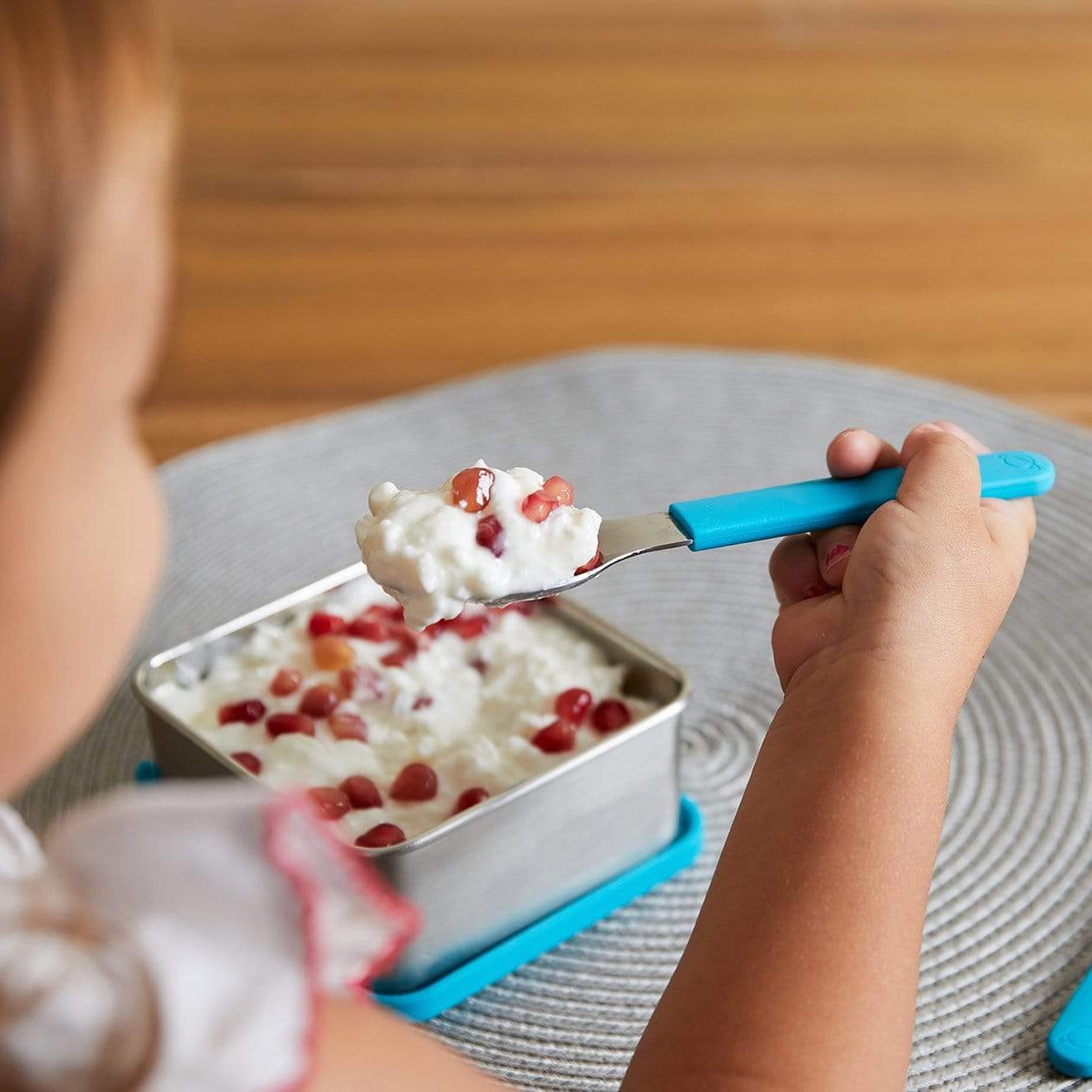 Young child eating cottage cheese and fruit  with Scuba Blue utensil set. 